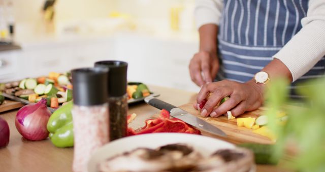 Person preparing meal by cutting various vegetables on kitchen counter. Ideal for content related to home cooking, culinary arts, and healthy eating. Suitable for articles, blogs, social media, and advertisements promoting fresh and healthy home-cooked meals.