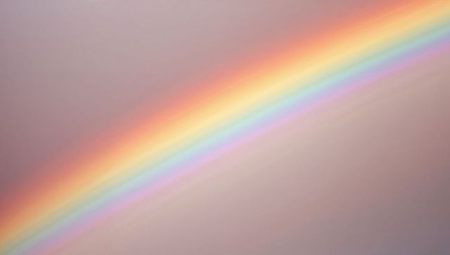 Diagonal pastel rainbow band crossing muted gray-pink sky with soft blended colors