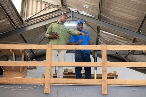 African american supervisors pointing at machinery on mezzanine in industrial workshop