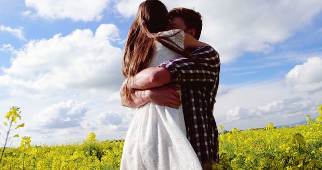 This image captures a couple embracing in a vibrant flower field under a bright, sunny sky. The natural setting and affectionately close pose make it ideal for use in campaigns focused on love and relationships, nature and outdoors, or happiness and well-being. It can also be used for greeting cards, wedding invitations, romantic getaway promotions, and lifestyle blogs.