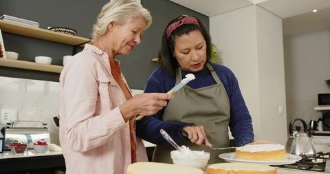 Senior Friends Collaborating on Cake Decorating in Home Kitchen