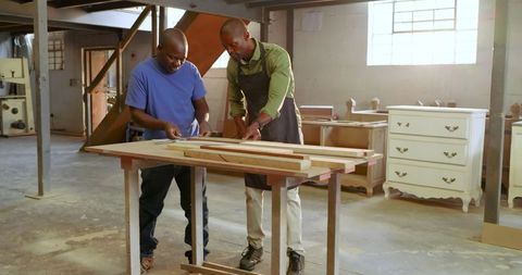 African american colleagues measuring wood in workshop