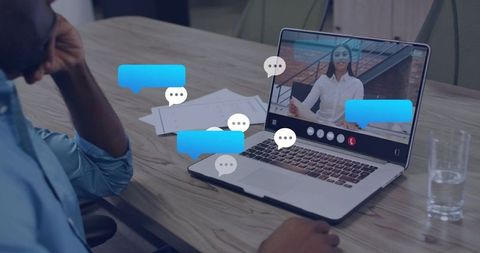 Employee watching remote presenter during virtual meeting with live chat overlays