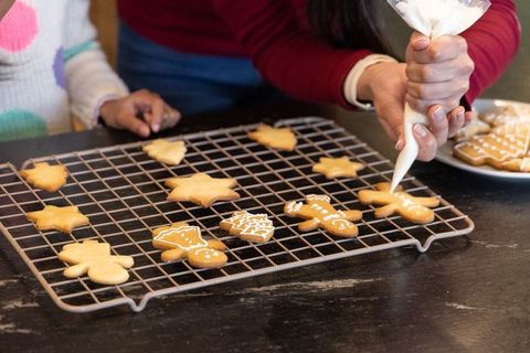 Mother and child decorating star and gingerbread cookies using piping bag