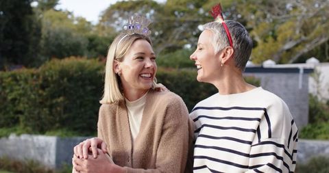 Laughing women wearing festive headbands in garden celebrating friendship and joy