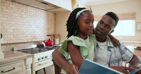Father and Daughter Sharing a Joyful Moment Reading in Kitchen