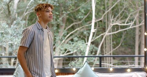 Young Man Relaxing on Outdoor Deck with String Lights and Forest View