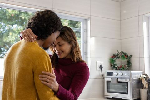 Couple embracing in sunlit kitchen celebrating cozy holiday moment