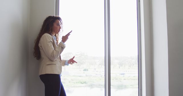 Businesswoman Speaking on Phone Near Large Window - Download Free Stock Images Pikwizard.com