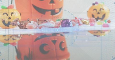 Halloween candy and jack-o'-lantern reflection on glossy tabletop with blue digital overlay