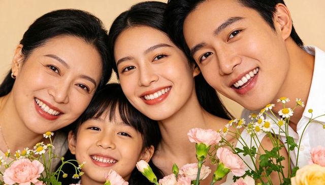 Smiling family leaning together holding pastel flowers, celebrating warmth and closeness
