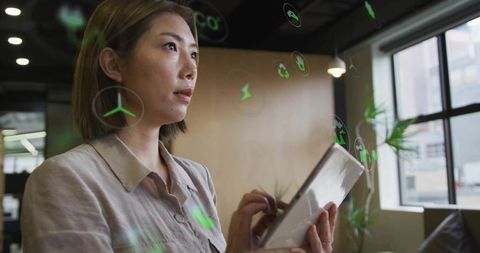Asian Woman Engaging with Digital Eco Icons in Modern Office