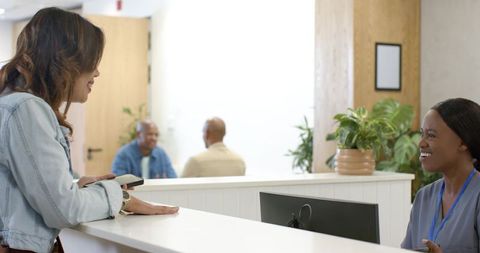 Patient checking in at clinic reception desk with smiling receptionist in scrubs