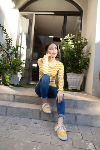 Thoughtful young woman sitting on steps near elegant glass entrance