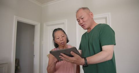 Senior asian couple exercising with tablet guidance at home
