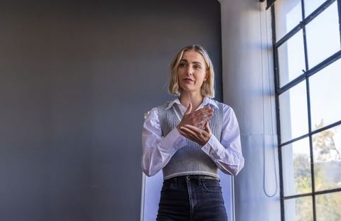Female presenter speaking and gesturing in minimalist industrial office with natural light
