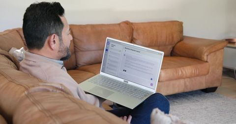 Man Relaxed Using Laptop on Leather Sofa at Home