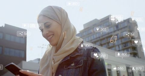 Smiling woman in headscarf tapping smartphone sunlit city social media engagement icons