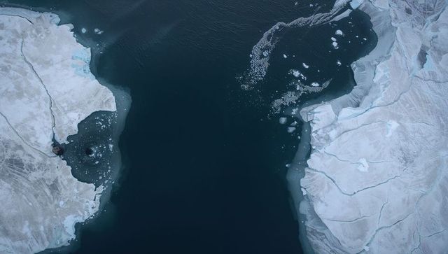 Aerial view showing dark polar channel between icy headlands with drifting sea ice floes