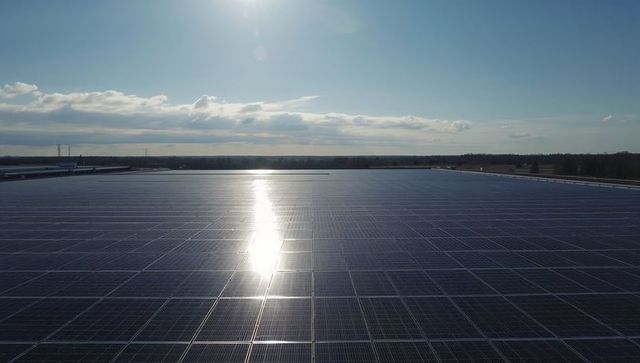 Expansive rooftop solar panel array reflecting sunlight across horizon with clear blue sky