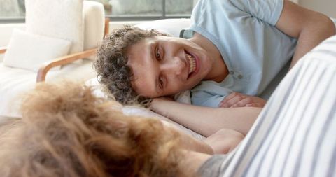 Happy couple lying in bed enjoying intimate conversation