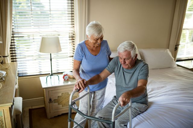 Senior woman helping man to walk with a walker at home