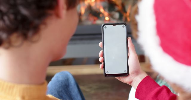People using smartphone in front of fireplace during Christmas holiday - Download Free Stock Images Pikwizard.com