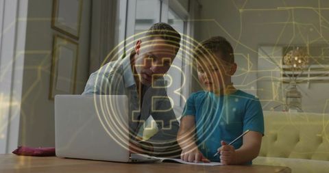 Father teaching son Bitcoin basics at home using laptop and notebook with blockchain overlay