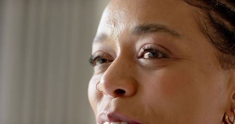 Closeup portrait woman gazing with nose hoop braided hair soft sidelight and gold earring