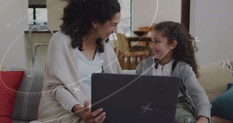 Mother and daughter sharing laptop on cozy room couch, smiling, bonding, remote learning