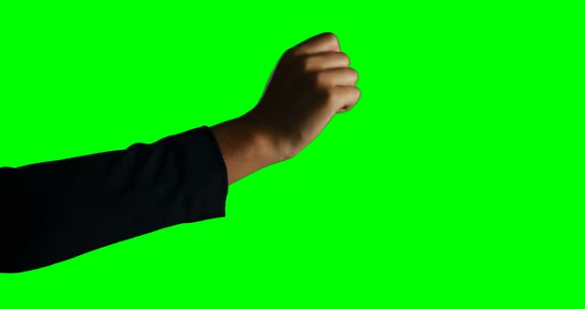 Outstretched arm with clenched fist against green screen background allows for easy background changes. Useful in projects requiring symbols of determination, strength, activism, or resistance.