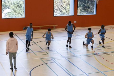 Diverse Basketball Team Practicing Lunges with Coach Guidance