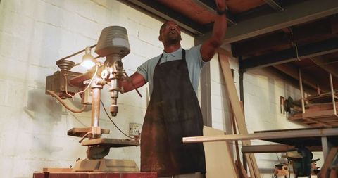 Skilled craftsman utilizing drill press in sawmill workshop