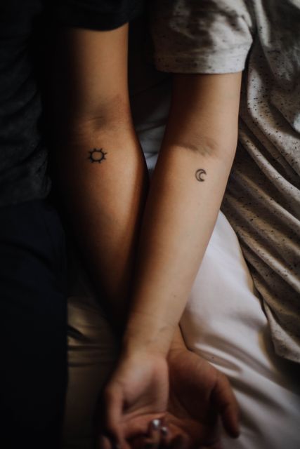Illustrating a couple with matching sun and moon tattoos, symbolizing their unique bond and connection. This close-up view captures the depth of their relationship, perfect for topics like love, togetherness, and personal expression. Useful for articles on couple dynamics, tattoo art, and symbols of love.