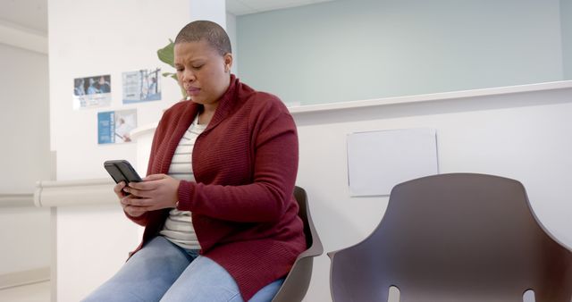 Sad african american woman using smartphone in waiting room in hospital, copy space. Medicine, healthcare, communication and hospital, unaltered.