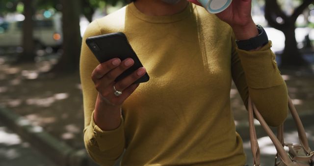 Woman drinking coffee and using smartphone in park - Download Free Stock Images Pikwizard.com