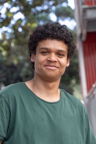 Friendly african american young man smiling outdoors in green t-shirt, casual portrait