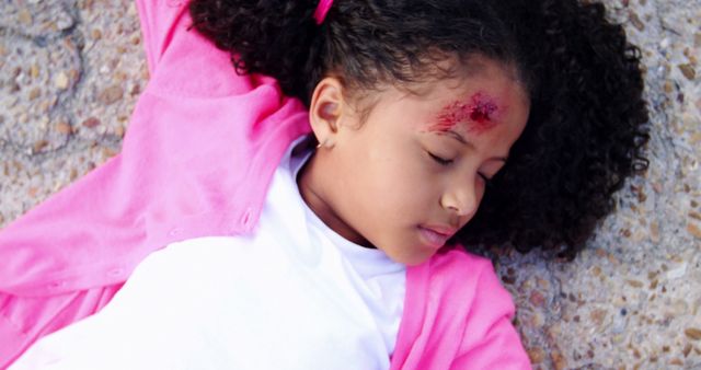 Injured Child Lying on Ground with Forehead Wound in Pink Jacket - Download Free Stock Images Pikwizard.com