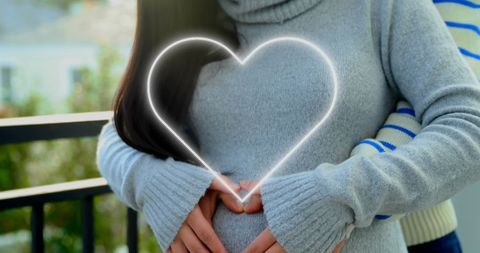 Happy Couple Celebrating Pregnancy with Neon Heart Symbol