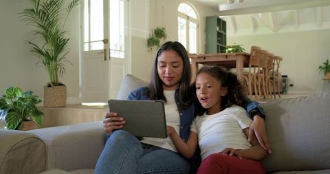 Mother and Daughter Sharing Tablet on Couch Cozy Family Learning and Bonding at Home