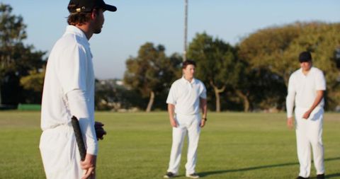 Cricket players preparing to bowl during golden hour on grassy outdoor sports field