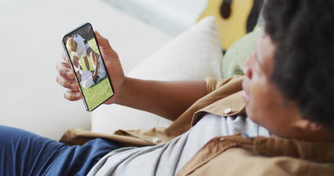 Man Watching Soccer Game on Smartphone at Home