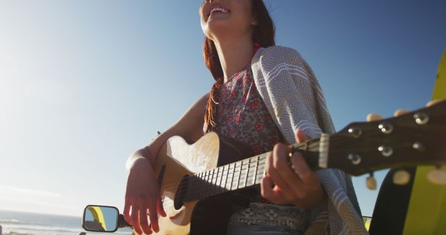 Happy caucasian woman sitting in beach buggy by the sea playing guitar - Download Free Stock Photos Pikwizard.com