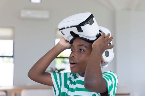 African american boy discovering virtual reality with white vr headset in bright home
