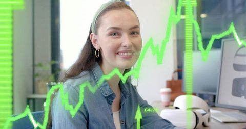 Smiling woman analyzing financial charts with VR headset at contemporary tech workspace