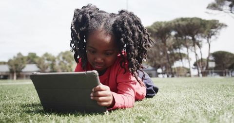Young Girl Using Tablet Outdoors in Park