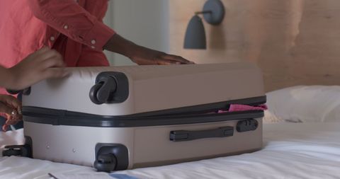 Closing Beige Luggage on Bed: Travel Preparation Scene