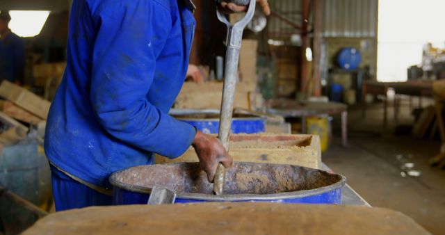 Worker working in foundry workshop. Worker steering in metal galleon with shovel 4k