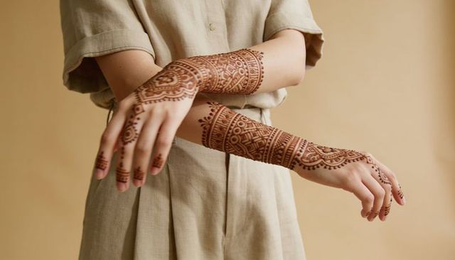 Woman crossing arms showing intricate henna mehndi designs on hands and forearms