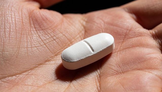 Macro close-up hand holding white scored tablet on palm for medicine and healthcare